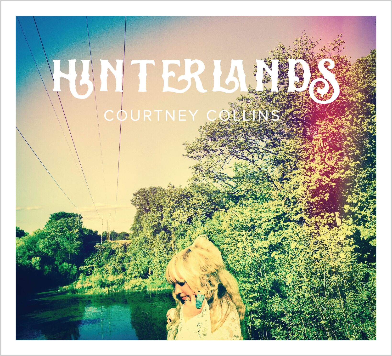 Courtney Collins' "Hinterlands" album cover: woman with blonde hair, trees, water, and sky.
