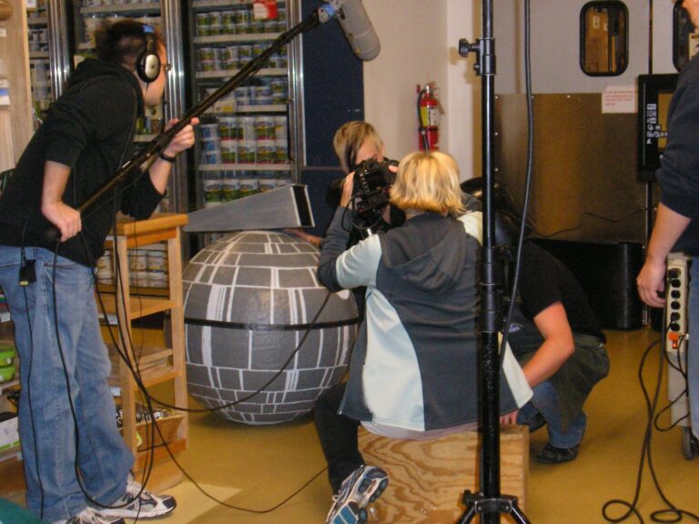 Film crew records a large Death Star prop with a boom mic and camera.