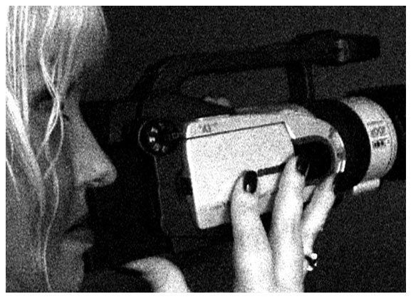 Woman filming with a vintage camcorder, close-up profile.